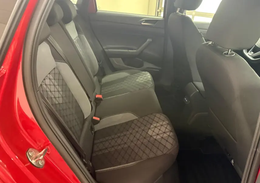 Vue intérieure arrière côté gauche d'une Volkswagen Polo Rouge Roi, sièges tissu avec motif géométrique et surpiqûres blanches.