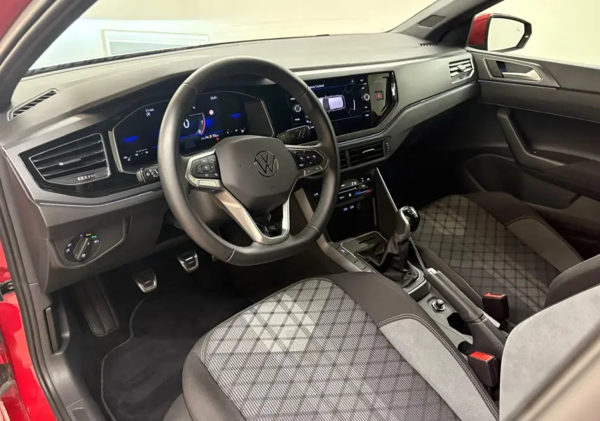 Vue intérieure côté conducteur de la Volkswagen Polo Rouge Roi 2025, volant multifonction et sièges tissu à motifs.