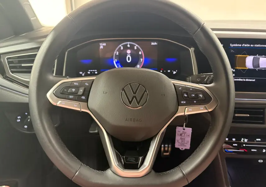 Vue rapprochée du volant multifonction noir avec logo VW et tableau de bord digital d'une Volkswagen Polo 2025.