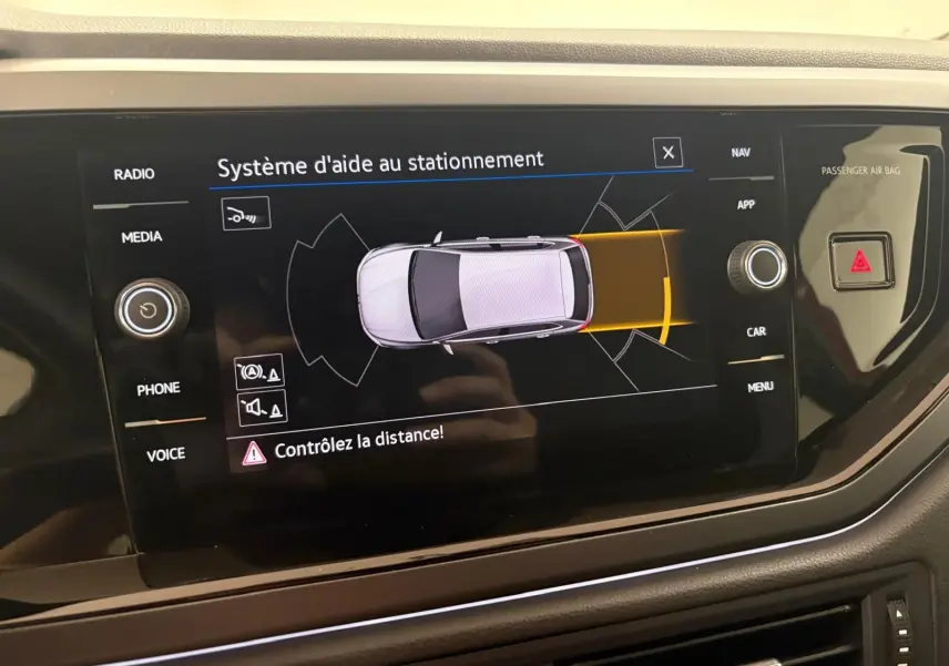 Écran central du système d'aide au stationnement de la Volkswagen Polo 2025 affichant une vue aérienne du véhicule en gris.