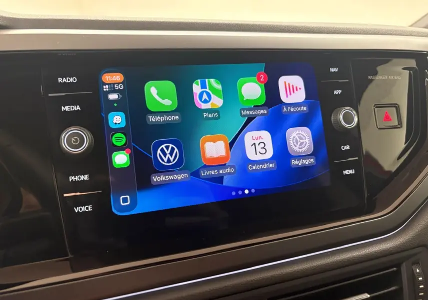 Écran tactile central de la Volkswagen Polo 2025 affichant les applications connectées, entouré de commandes noires brillantes.
