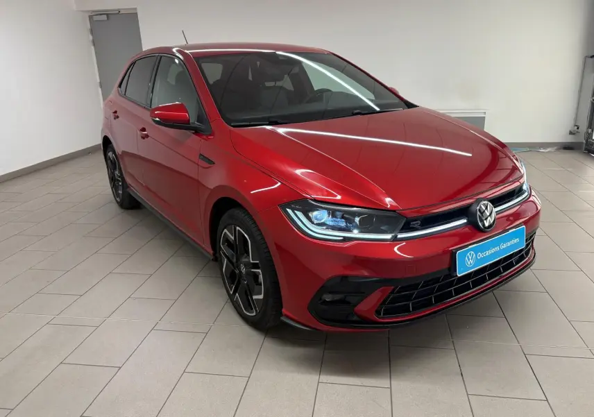 Volkswagen Polo 1.0 TSI R-Line rouge métallisé vue 3/4 avant droit en intérieur sur sol carrelé.