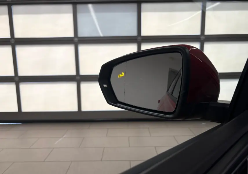 Rétroviseur extérieur côté gauche rouge métallisé de la Volkswagen Polo 1.0 TSI R-Line avec alerte angle mort allumée.