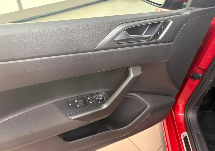 Vue intérieure sur la porte avant gauche rouge Roi d'une Volkswagen Polo 2025 avec commandes de vitres et verrouillage.