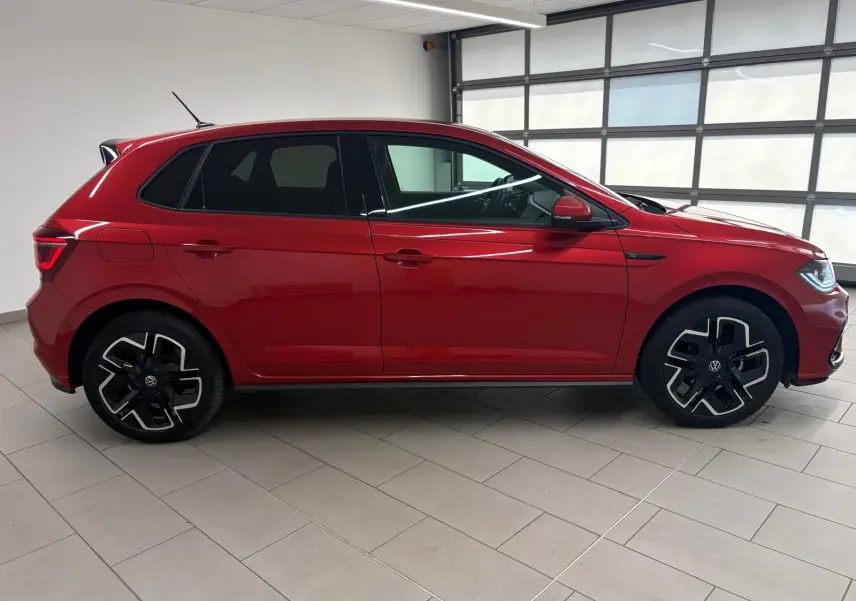 Profil droit d'une Volkswagen Polo 1.0 TSI 95 R-Line rouge métallisé, avec jantes noires et détails sportifs visibles.