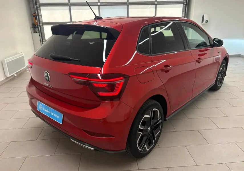 Vue 3/4 arrière droite d'une Volkswagen Polo 2025 Rouge Roi métallisée avec finition R-Line et jantes alliage distinctives.