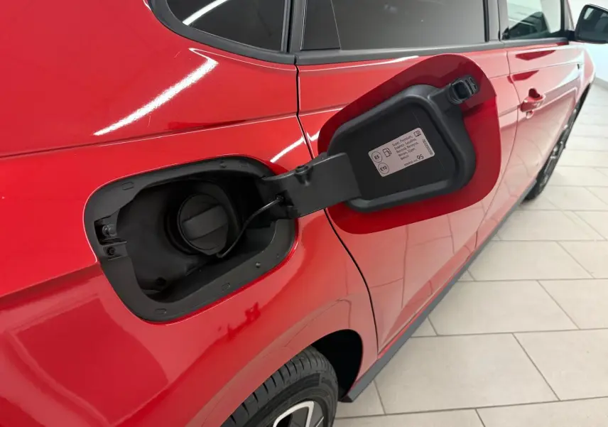 Vue côté gauche arrière d'une Volkswagen Polo Rouge Roi avec trappe de carburant essence ouverte, peinture métallisée brillante.
