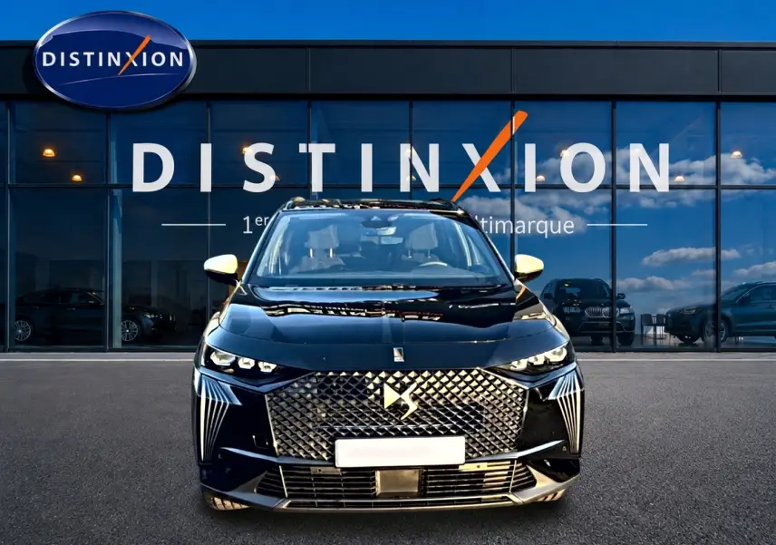 Vue avant d'un DS7 noir 2026 avec calandre diamantée et phares LED distinctifs, devant une vitrine Distinxion.