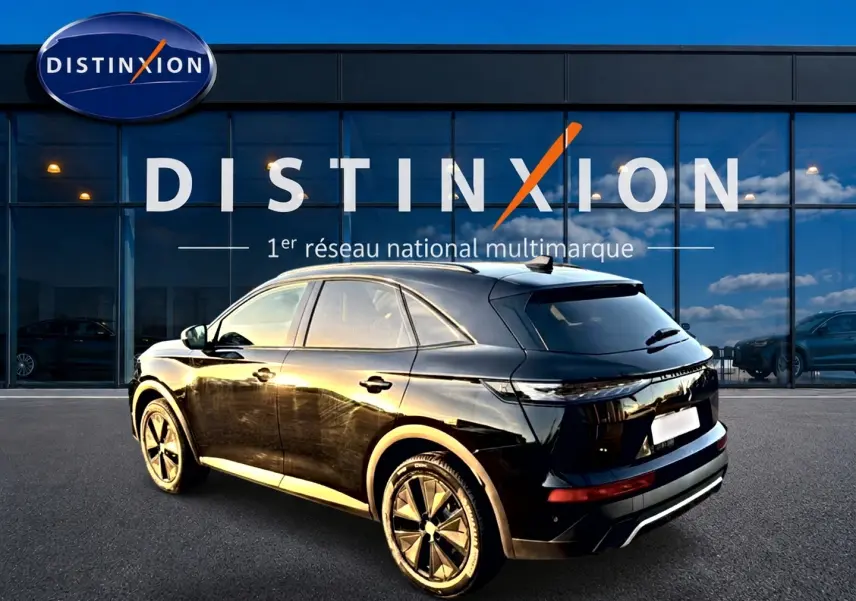 DS7 noir vue 3/4 arrière droit, avec jantes alu et vitres arrière surteintées devant un bâtiment Distinxion.