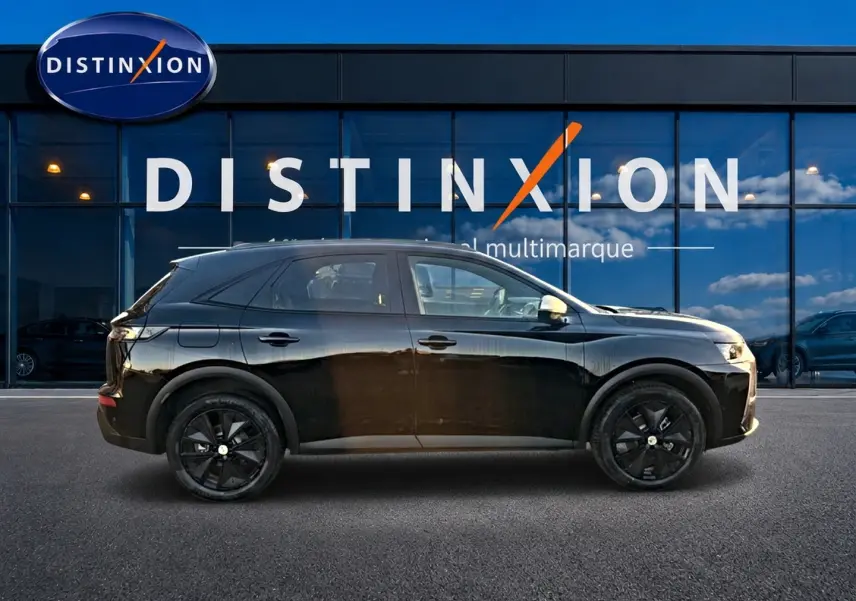 Vue latérale gauche d'un DS7 noir 2026 garé devant une vitrine avec logo Distinxion, jantes noires visibles.