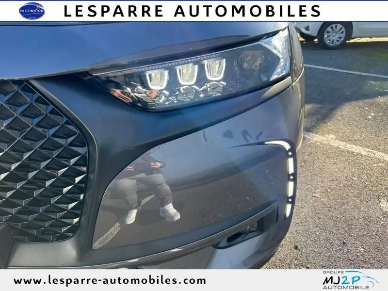 Gros plan sur le phare avant droit et la calandre noire du DS7 Crossback gris hybride rechargeable 2021.