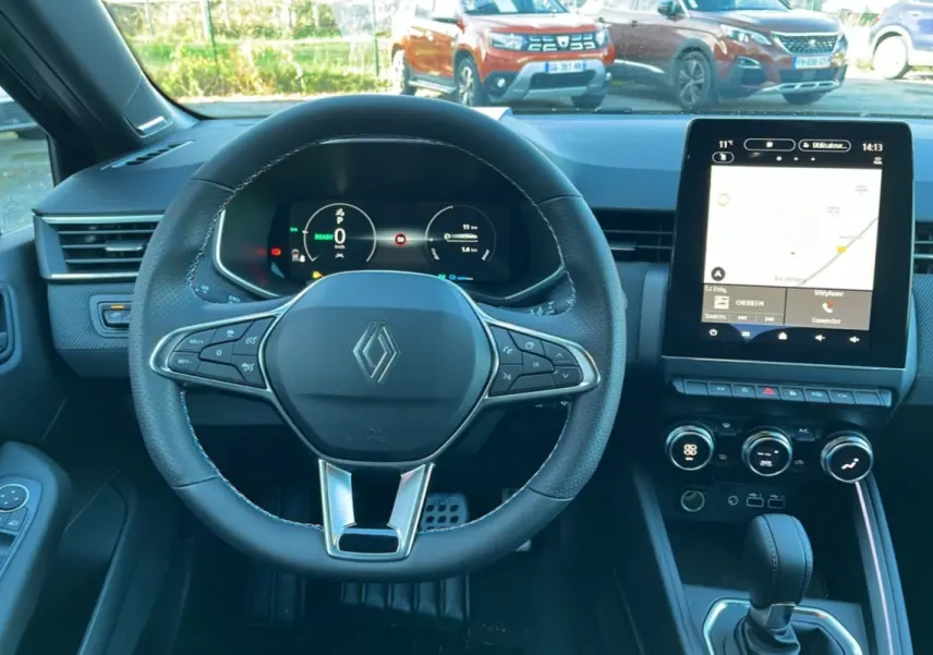 Vue intérieure centrée sur le volant cuir multifonctions et l’écran tactile du tableau de bord de la Renault Clio V E-Tech 145.