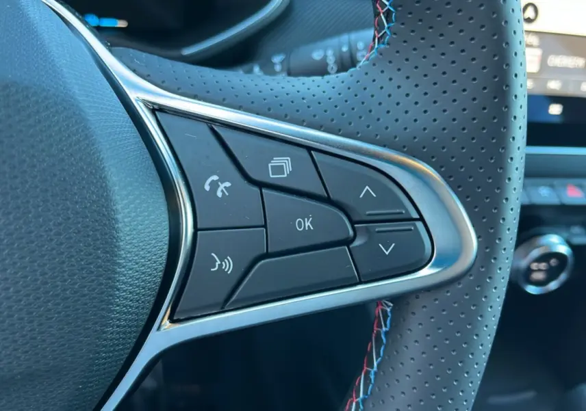 Gros plan sur les commandes multifonctions à droite du volant cuir perforé de la Renault Clio V E-Tech 145 Esprit Alpine Bose noire.