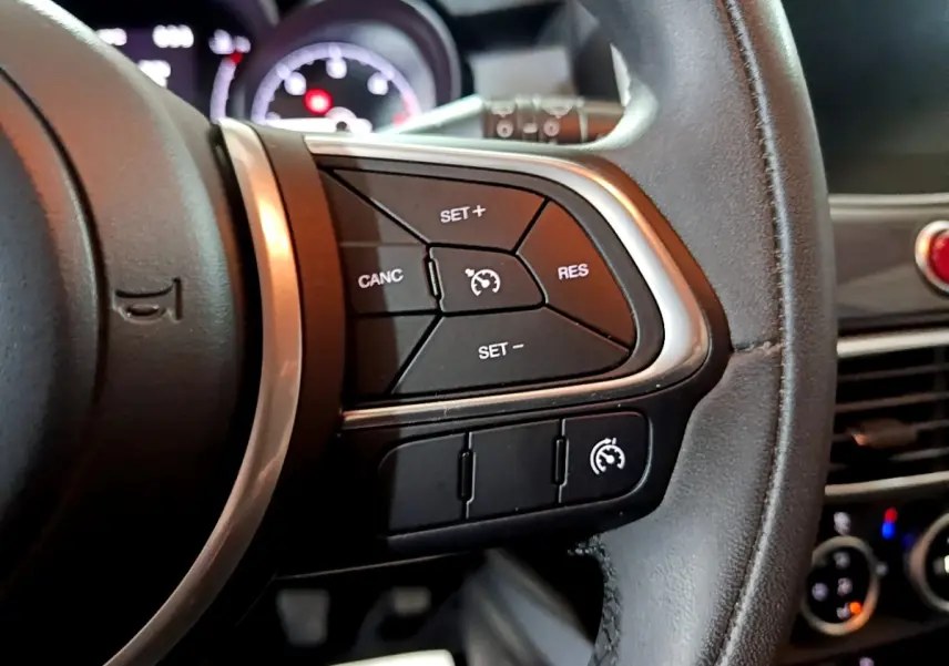 Gros plan sur la partie droite du volant noir du Fiat 500X 2019, avec commandes du régulateur de vitesse visibles.
