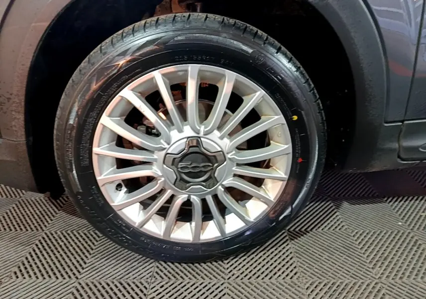 Gros plan sur la roue avant gauche gris foncé d'une FIAT 500X 1.6 Multijet avec jante alliage à rayons fins.