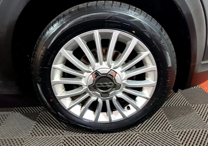 Gros plan sur la roue avant droite avec jante alliage argentée du FIAT 500X gris foncé City Cross 2019.