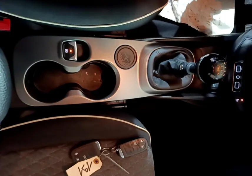 Vue plongeante sur la console centrale de la Fiat 500X gris foncé, avec levier de vitesses manuel et porte-gobelets.