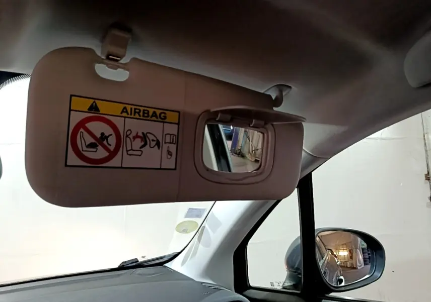 Détail intérieur du pare-soleil côté conducteur avec miroir et avertissement airbag dans une Fiat 500X gris foncé.