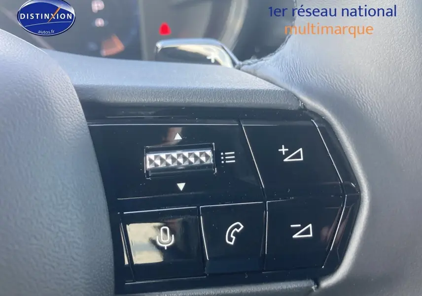 Gros plan sur les commandes au volant noir de l'Alfa Romeo Junior 1.2 hybride, avec boutons de volume et appels.