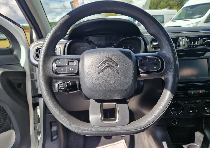 Vue centrée sur le volant noir du Citroën C3 Société blanc, montrant les commandes intégrées et le tableau de bord.