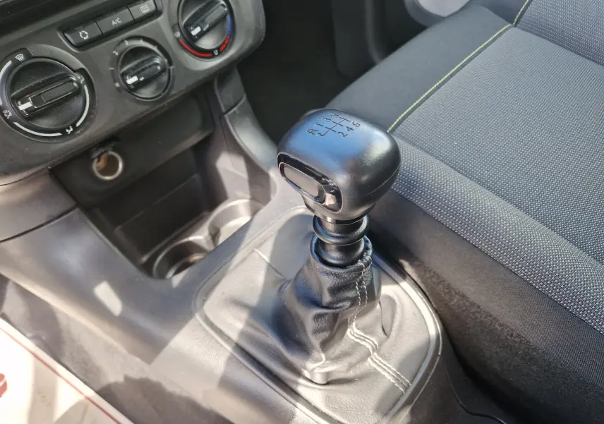 Gros plan sur le levier de vitesses manuel noir et la console centrale du Citroën C3 Société blanc, avec siège tissu gris à coutures claires.