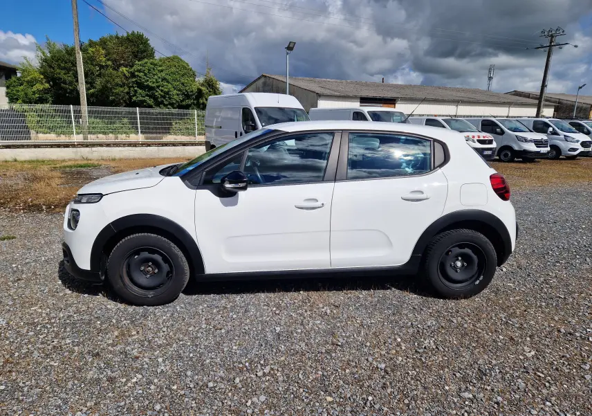 Vue latérale droite d'une Citroën C3 Société blanche de 2021 avec jantes acier noires sur un parking extérieur.