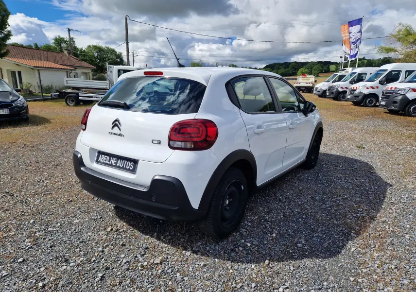 Vue 3/4 arrière droite d'une Citroën C3 Société blanche 2021 avec pare-chocs noirs et jantes tôles noires.