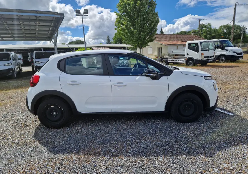 Vue de profil côté gauche d'une Citroën C3 Société blanche de 2021 avec jantes tôles noires sur un parking extérieur.