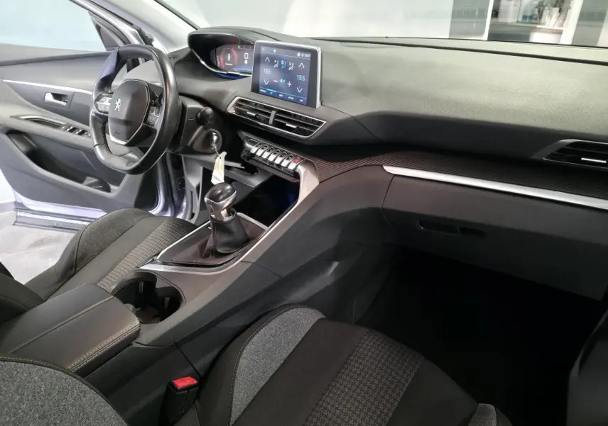 Vue intérieure côté conducteur du Peugeot 3008 gris, mettant en valeur le tableau de bord avec écran tactile et la boîte manuelle.