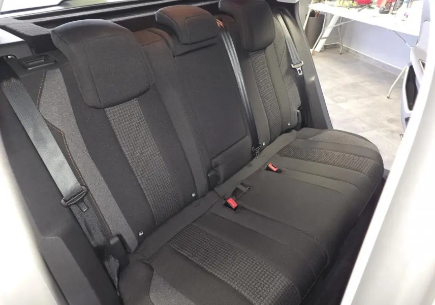 Vue intérieure de la banquette arrière noire en tissu du Peugeot 3008 gris, avec ceintures de sécurité visibles.
