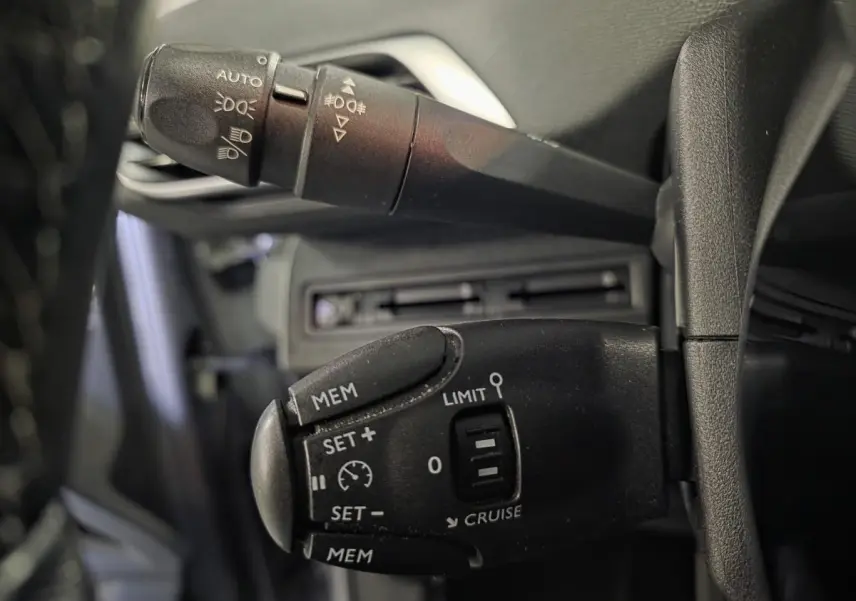 Gros plan sur les commandes de régulateur et feux du Peugeot 3008 gris, côté gauche du volant.