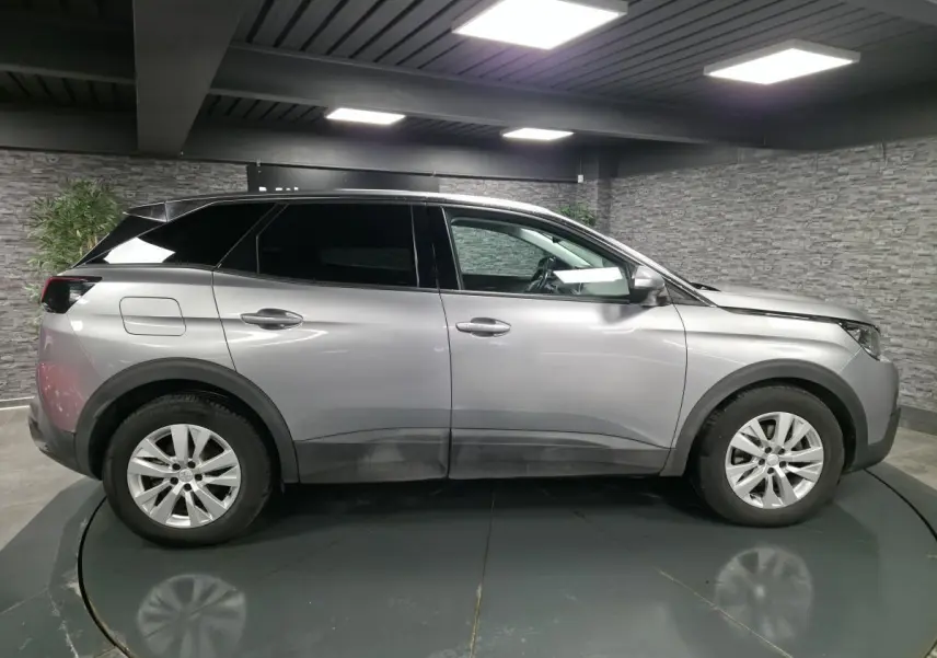 Vue profil droit d’un Peugeot 3008 gris métallisé 2018 avec jantes alliage 17 pouces dans un garage.