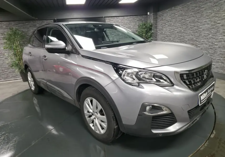 Peugeot 3008 gris métallisé vue 3/4 avant droit en intérieur avec calandre chromée et jantes alliage 17 pouces.