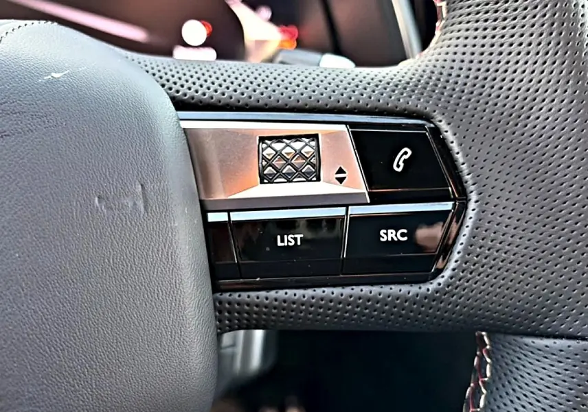 Gros plan sur les commandes gauche du volant en cuir perforé noir du DS7 1.5 BlueHDi 130 Performance Line 2026.