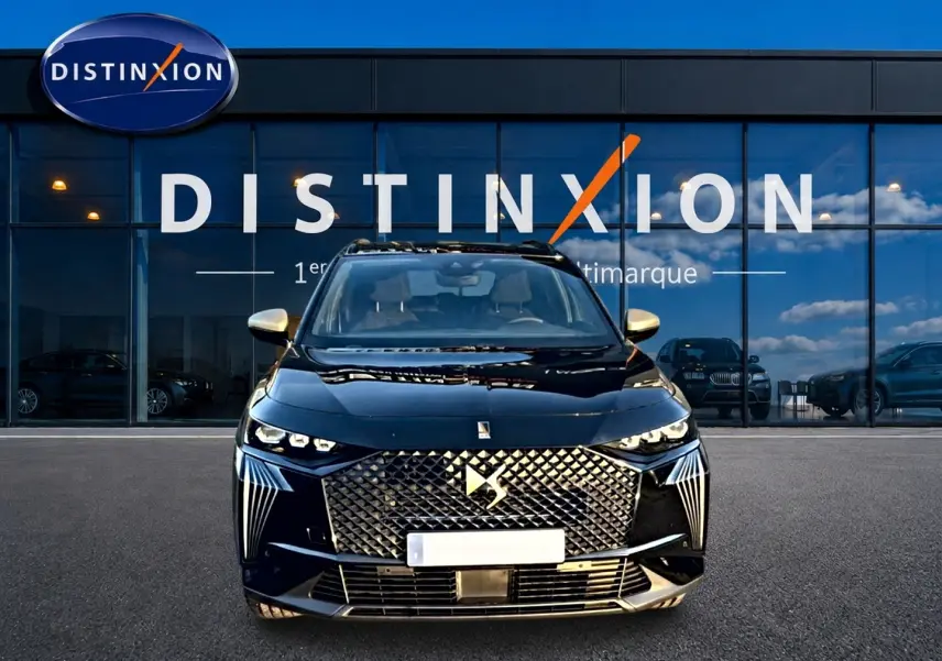 Vue de face d'un DS7 noir 2026 avec calandre diamantée et phares LED distinctifs, devant une vitrine Distinxion.