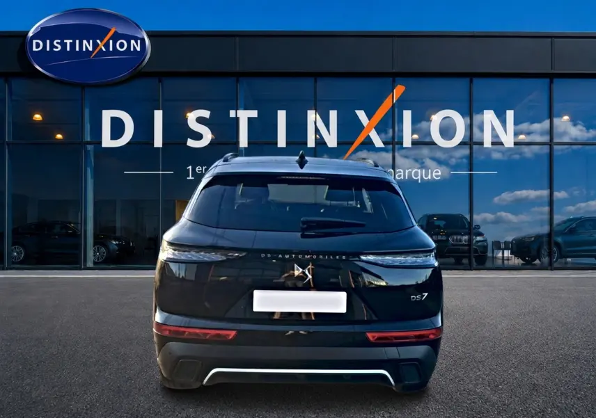 Vue arrière d'un DS7 noir 2026 garé devant une vitrine avec logo Distinxion en arrière-plan.