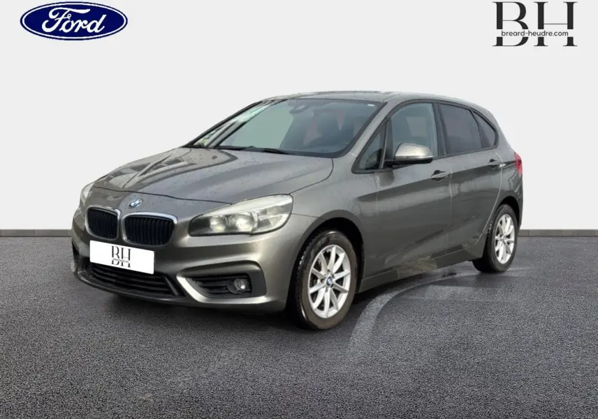 BMW Série 2 Active Tourer 216dA gris platine vue 3/4 avant droit avec jantes alu et feux allumés.