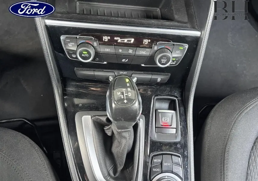 Console centrale vue de dessus avec levier de vitesses automatique noir et commandes de climatisation dans un intérieur tissu anthracite.