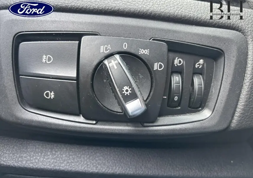 Gros plan sur le panneau de commandes des phares noir dans l’habitacle d’une BMW Série 2 Active Tourer platinumsilber.