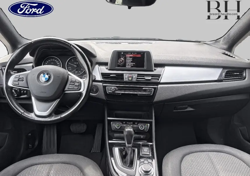 Vue frontale de l'habitacle BMW Série 2 Active Tourer 216dA 2015, avec volant cuir multifonction et console centrale noire.