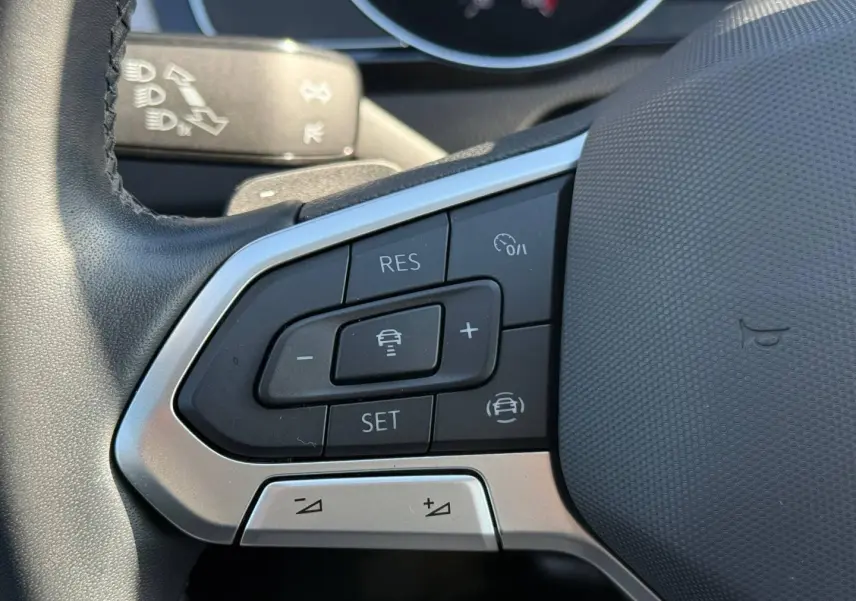 Gros plan sur les commandes de régulateur de vitesse au volant cuir noir d'une Volkswagen Passat SW 2023.
