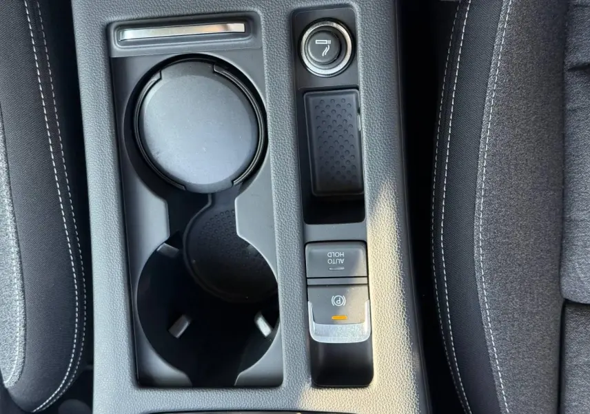 Vue plongeante sur la console centrale noire de la Volkswagen Passat SW 2023, avec porte-gobelets et frein électrique.