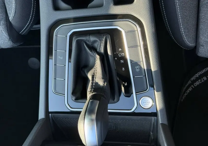 Gros plan sur la console centrale de la Volkswagen Passat SW 2023, levier de vitesse cuir noir et boutons autour.