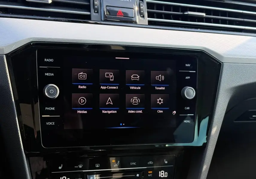Écran tactile central de la Volkswagen Passat SW 2023, vue rapprochée du tableau de bord noir avec commandes digitales.