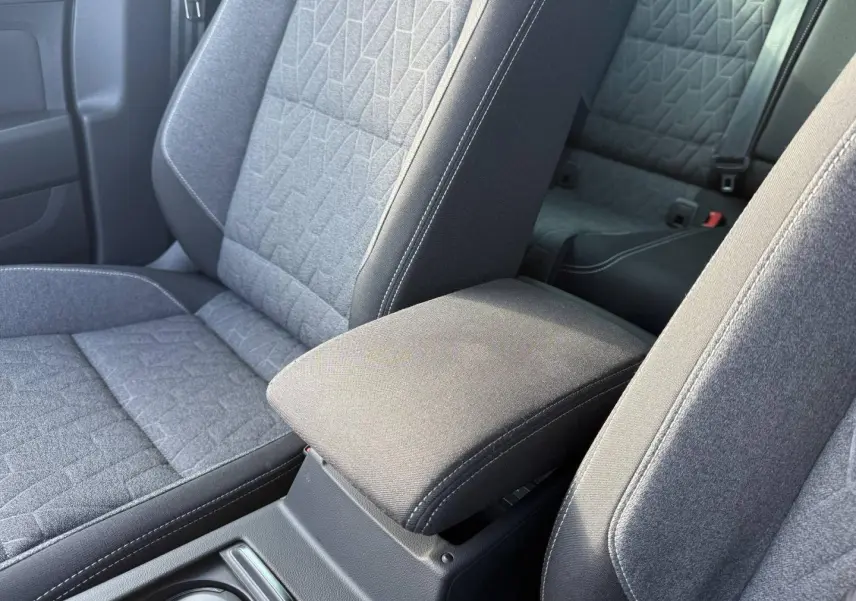 Accoudoir central avant et sièges tissu gris avec surpiqûres blanches dans l'habitacle de la Volkswagen Passat SW 2023.