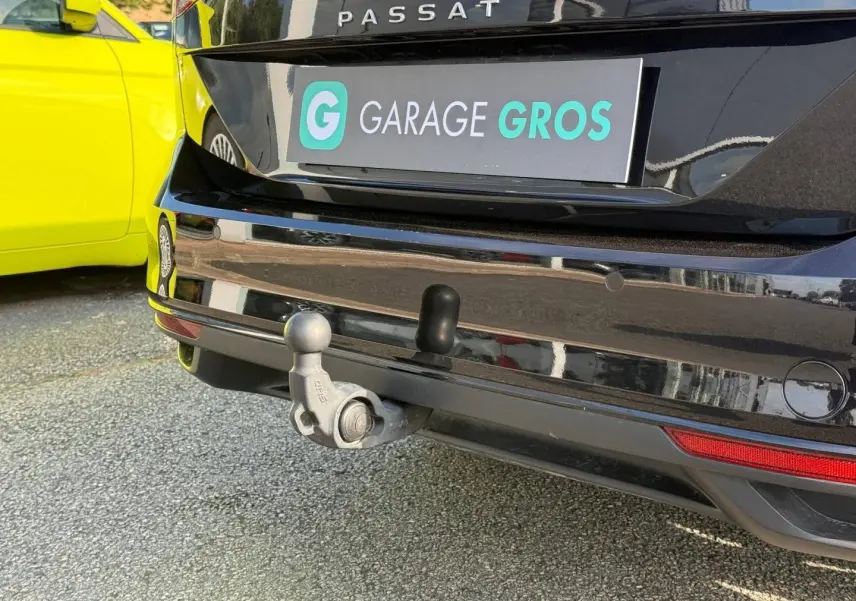 Vue rapprochée arrière d’une Volkswagen Passat SW noire intense nacrée avec attelage visible et plaque Garage Gros.