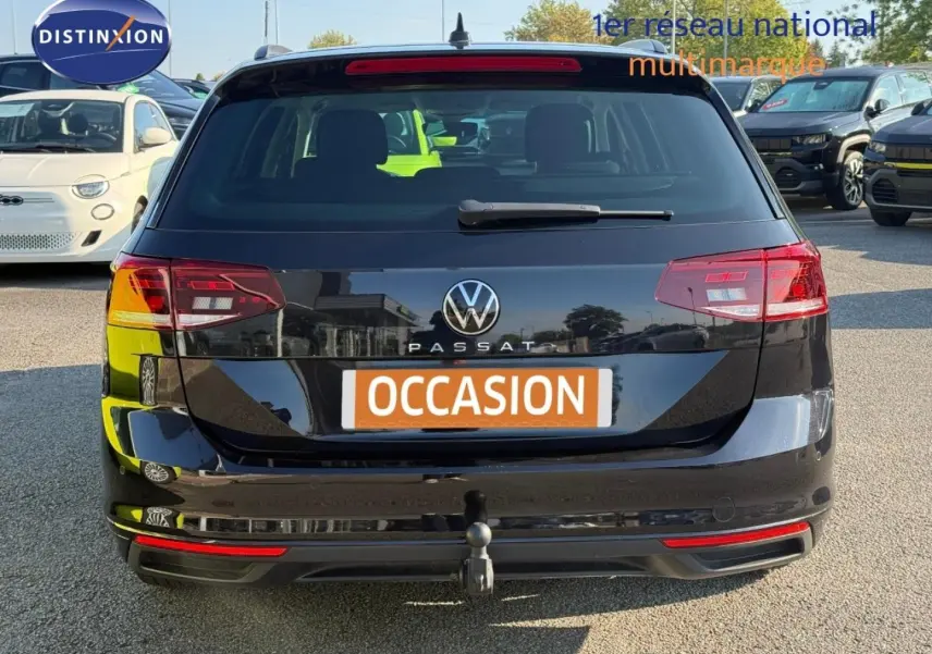 Vue arrière d'une Volkswagen Passat SW noire intense nacrée avec attelage et feux arrière LED visibles.