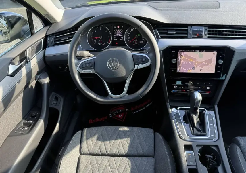 Vue intérieure de la Volkswagen Passat SW 2023, tableau de bord noir avec volant cuir multifonction et écran tactile GPS.