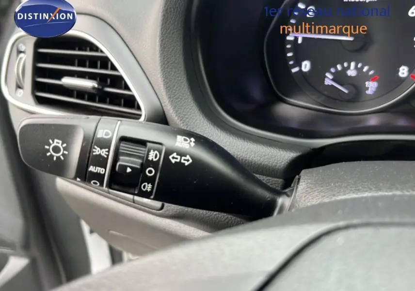 Gros plan sur la commande des phares et clignotants côté gauche du tableau de bord d’une Hyundai i30 blanche nacrée 2023.