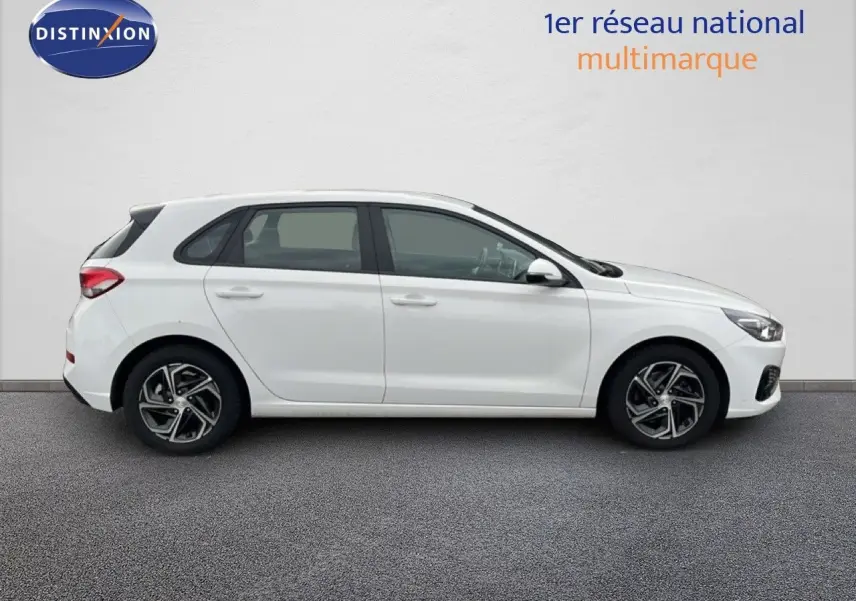 Profil droit d'une Hyundai i30 2023 blanc nacré, compacte 5 portes avec jantes alliage bicolores.